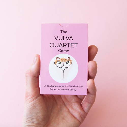Hand holding up the Vulva Quartet game box on a pink backdrop