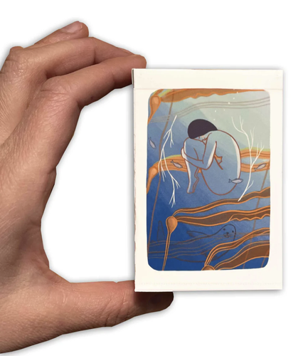 The Gentle Tarot linen edition hand holding closed box between thumb and index finger on white background