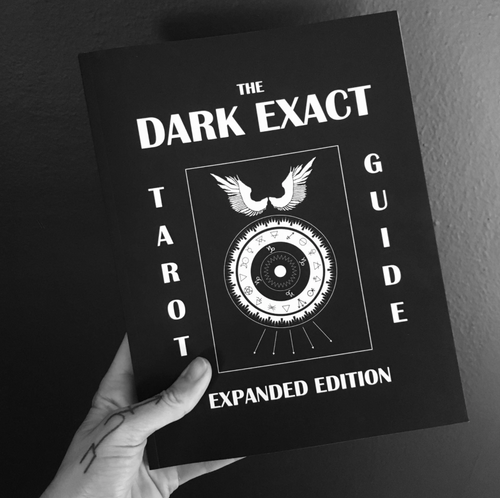 The Dark Exact Tarot guidebook held in someone's hand