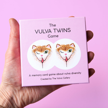 Load image into Gallery viewer, Hand holding the Vulva Twins game box on a pink background
